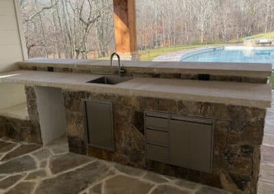 Closeup of outdoor stone kitchen with pool view Canton GA